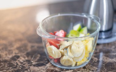 Şeffaf meyve kasesi ve içinde meyve suyu hazırlayan bıçak meyve, sağlık ve diyete iyi gelir..