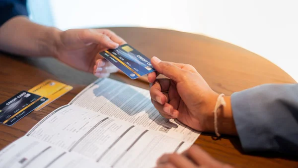 The bank clerk is presenting the benefit of the credit card to a customer who applied for a credit card service at the office.