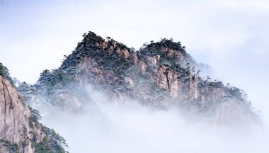 Huangshan Ulusal Parkı 'nın dağ tepelerindeki bulut ve çam ağacı manzarası. Huangshan Dağı 'nın kış mevsimi manzarası. UNESCO Dünya Mirası Alanı, Anhui Çin.