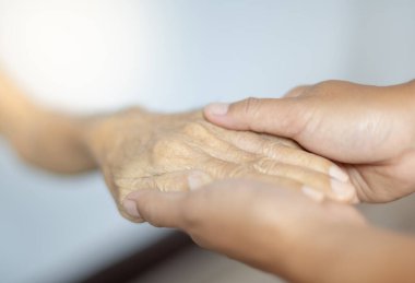 Babası sabırlıyken ve sağlıklarını geri kazanmalarını beklerken, yaşlı bir adamı desteklediği için babasıyla el ele tutuşan bir kadın..