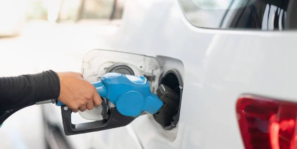 Female worker hand holding nozzle fuel fill oil into car tank at pump gas station, For the concept transportation power business technology concept.