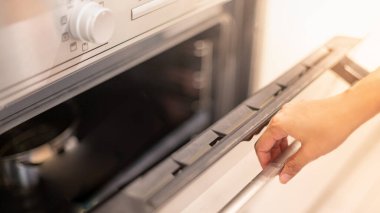 Kadın elli profesyonel aşçı elektrikli fırını açarken evde yemek hazırlıyor. Hobi, yaşam tarzı. Seçici odaklanma. Web Afişi