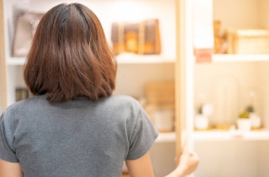 The back view of  woman and hand is opening the display cabinet with the glass door .