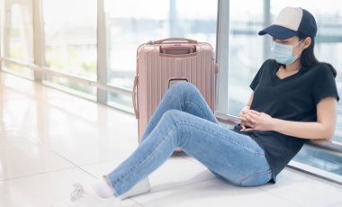 Kovid19 salgını nedeniyle havaalanındaki başka bir yere gitmek için kaçırılan ya da iptal edilen uçak nedeniyle üzgün ve depresif hisseden Asyalı kadın..