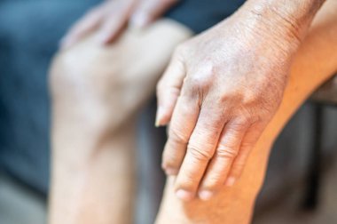 Elleri buruşuk ve besin yetersizliğinden morarmış yaşlı bir adamın eli..