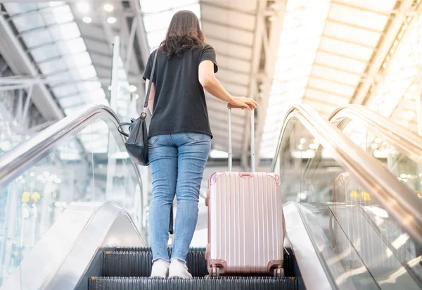 Aasian Tyttö Päällään Rento Paita Kuljettaa Matkalaukku Matkatavarat Liukuportaat Lentokentällä — kuvapankkivalokuva