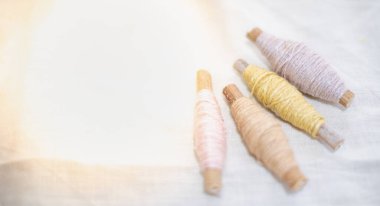 Pastel rengi işlemeli iplik rulosu giysi endüstrisinde kullanılıyor beyaz pamuk arka planda, pazarda dikiş malzemeleri satılıyor hobi, eğlence ve giysi endüstrisi konsepti için