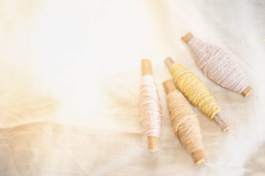 Pastel rengi işlemeli iplik rulosu giysi endüstrisinde kullanılıyor beyaz pamuk arka planda, pazarda dikiş malzemeleri satılıyor hobi, eğlence ve giysi endüstrisi konsepti için