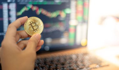 Kripto para birimi olan bir Altın Bitcoin, kripto para birimi grafiği olan bir iş kadınının elinde..