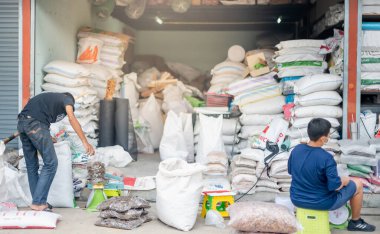 BANGKOK, THAILAND - 24 Ağustos 2021: İki işçi ağaç pazarındaki müşterilere satmak için toprak torbası hazırlayın.