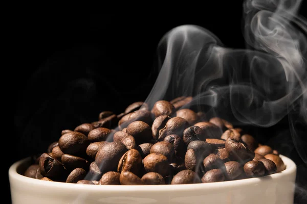 Tazza di caffè piena di chicchi di caffè con fumo — Foto Stock