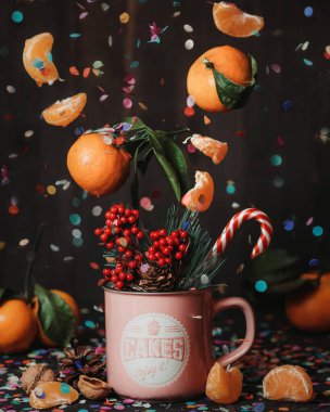 Mandalina dilimleri, konfeti ve noel şekerli ladin dalı pembe kupanın içine uçar. Mandalina çayı yapıyorum. Kışın sıcak bir içecek. Noel içkisi. Noel 'in büyüsü. Sihirli içecek. Havalanma.