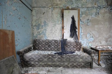 Ukrayna 'nın hayalet kasabası Pripyat yakınlarındaki Çernobil bölgesinde terk edilmiş bir tesiste kanepesi olan bir oda.
