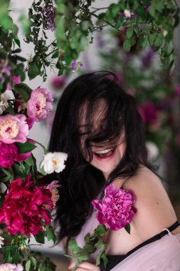 Beyaz, pembe ve mor çiçekleri olan sevimli genç bir kadının kapalı stüdyo fotoğrafları..