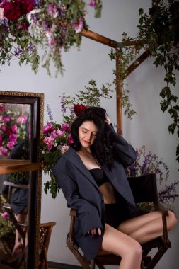 Beyaz, pembe ve mor çiçekleri olan sevimli genç bir kadının kapalı stüdyo fotoğrafları..