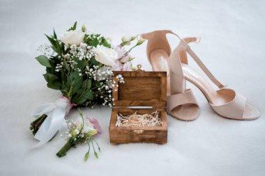 Düğün buketi, yaka çiçeği, beyaz arka planda yüzükler ve ayakkabılar