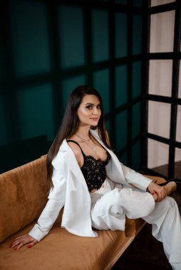 Beyaz takım elbiseli, oldukça seksi esmer bir kadının moda portresi.