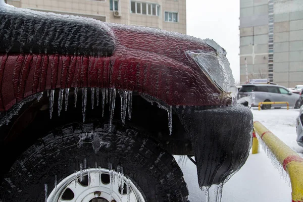 El guardabarros rojo, la rueda y el parachoques del SUV están muy helados debido a la lluvia en invierno. Icicles cuelgan. — Foto de Stock