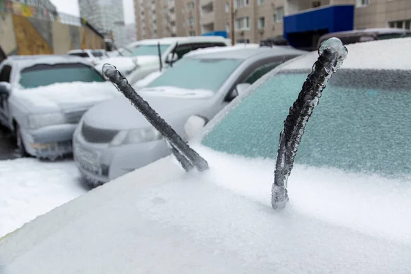 Los limpiaparabrisas de un coche de pasajeros blanco son muy helados debido a la nieve húmeda en invierno. Bloqueado por el hielo. Fotos De Stock