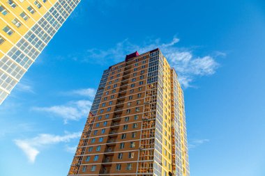 Gökyüzünün arka planına karşı tuğla ve camdan yapılmış modern çok katlı binalar. Kahverengi, bej. İnşaat.