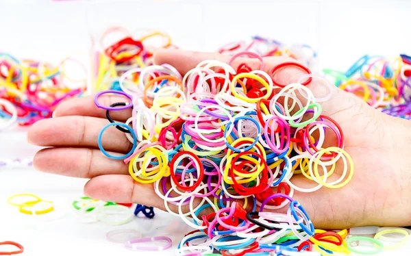 Mani e mucchio di piccoli elastici rotondi colorati arcobaleno colo — Foto Stock