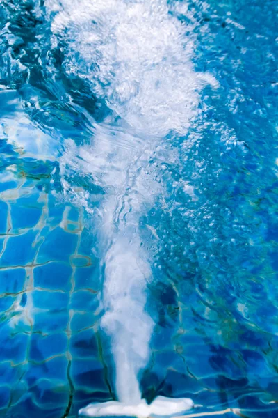 Água jorrando para fora do buraco perto da parede da piscina . — Fotografia de Stock