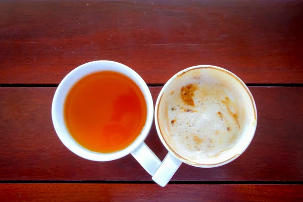Вкусная чашка до совершенно пустой чашки кофе на деревянном столе — стоковое фото