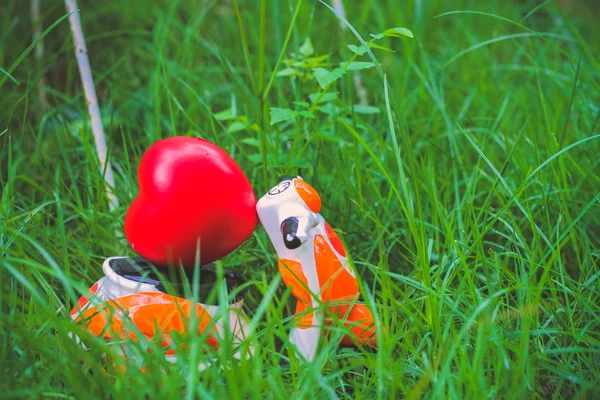 Motocicleta miniatura que lleva un cojín rojo del corazón en la hierba —  Fotos de Stock