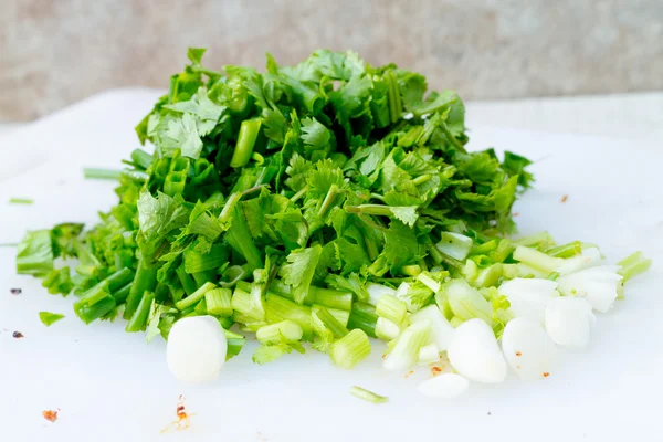 Geschnittene grüne Zwiebeln und gehackter frischer Koriander auf dem Boden — Stockfoto