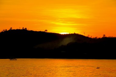 gün batımı tekne nehir san çalışan ile dağın arkasında