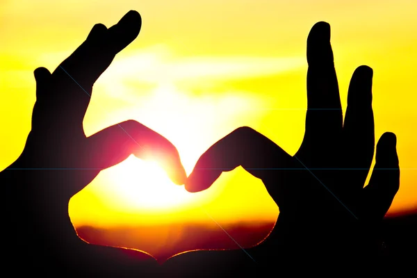 Сердце, сделанное двумя руками с заходом солнца — стоковое фото