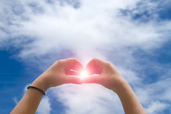 Símbolo do coração feito com duas mãos com o céu azul — Fotografia de Stock