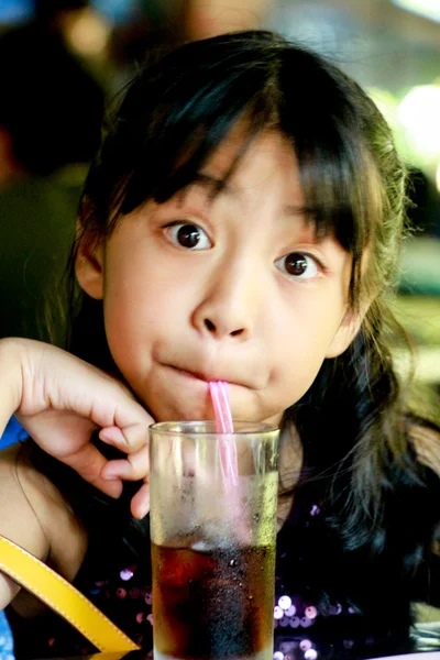 女の子がカメラを見てガラス管から水を吸う. — ストック写真