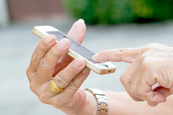 La mano del anciano sosteniendo tijeras y cortando el teléfono móvil . — Foto de Stock