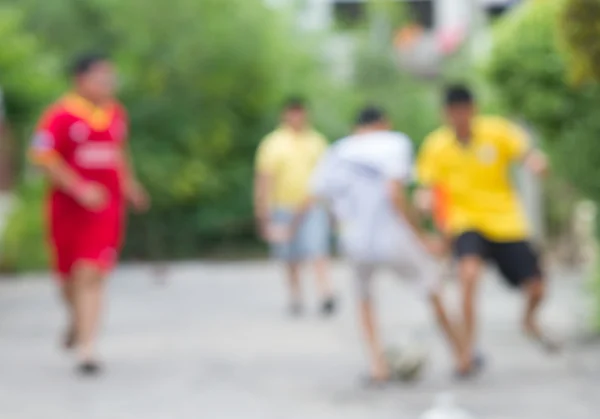 Blurry of young boy playing football on the concrete road — Stock Photo, Image