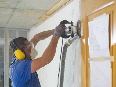 İşçi duvarları makinelerle yumuşatıyor.