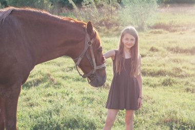 Onun atı okşayarak ve kameraya bakarak kız