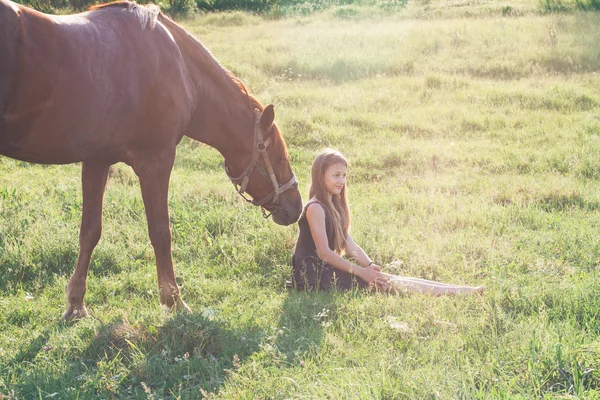 Meisje en haar paard op het zonovergoten veld — Stockfoto