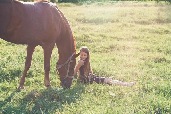 Meisje en haar paard op het zonovergoten veld — Stockfoto