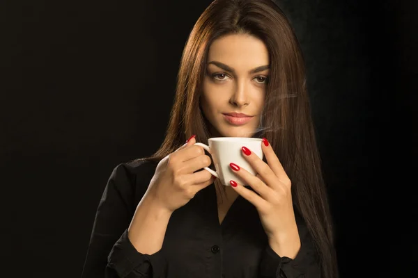 Porträtt av sexiga kvinna njuter av en varm kopp kaffe på en mörk ba — Stockfoto