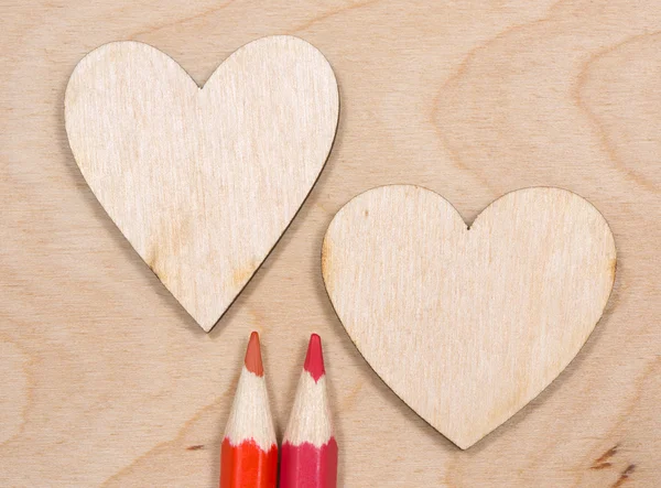 Wooden heart and red pencils on the plywood background