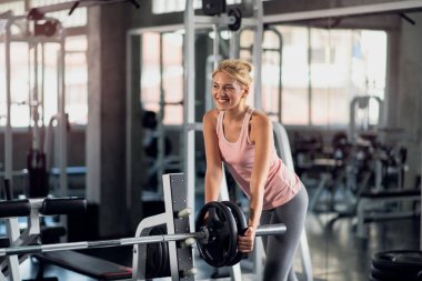 Güçlü bir kadın spor salonunda ağırlık plakasıyla egzersiz yapıyor spor salonunda egzersiz yapıyor.