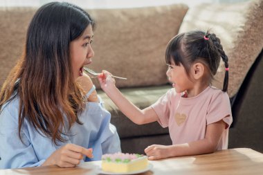 Mutlu Asyalı kız kardeşinin portresi ablasına lezzetli bir pasta kaşığı veriyor.