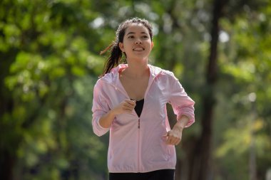 Sportif genç Asyalı koşucu kadın parkta, sporda ve sağlıklı yaşam tarzında koşuyor