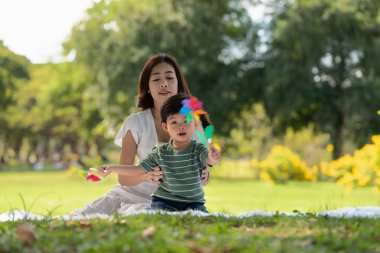 Mutlu Asyalı aile bahçede annesiyle yel değirmeni oynarken eğleniyor.