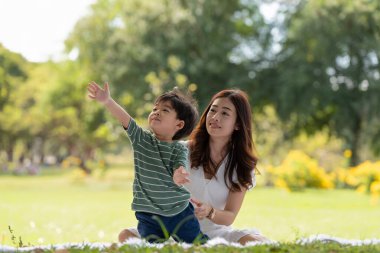 Mutlu Asyalı bir aile, annesi ve oğlu parkta oynarken eğleniyor.