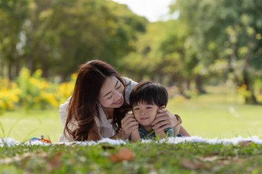 Mutlu Asyalı bir aile, annesi ve oğlu parkta oynarken eğleniyor.