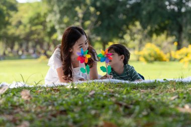 Mutlu Asyalı aile bahçede annesiyle yel değirmeni oynarken eğleniyor.