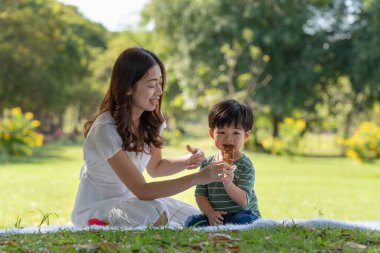 Mutlu Asyalı bir aile, parkta birlikte Tayland usulü ızgara domuz şiş yiyerek eğleniyor.