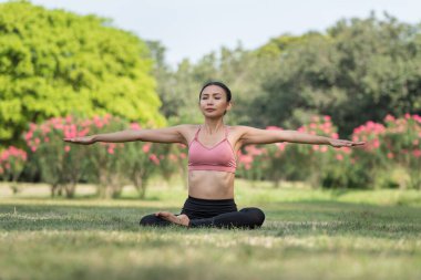 Asyalı bir kadın yoga yapıyor ve spor kıyafetleriyle parkta, spor salonunda ve sağlıklı yaşam tarzı konseptiyle rahatlıyor.